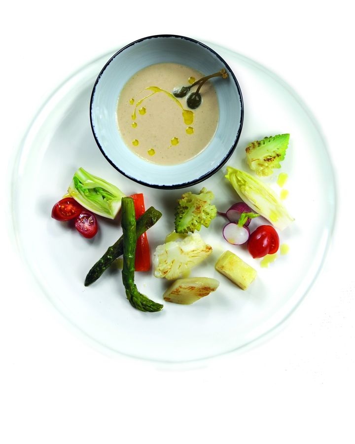 Verdure con una salsa e un filo d'olio a crudo su un piatto bianco